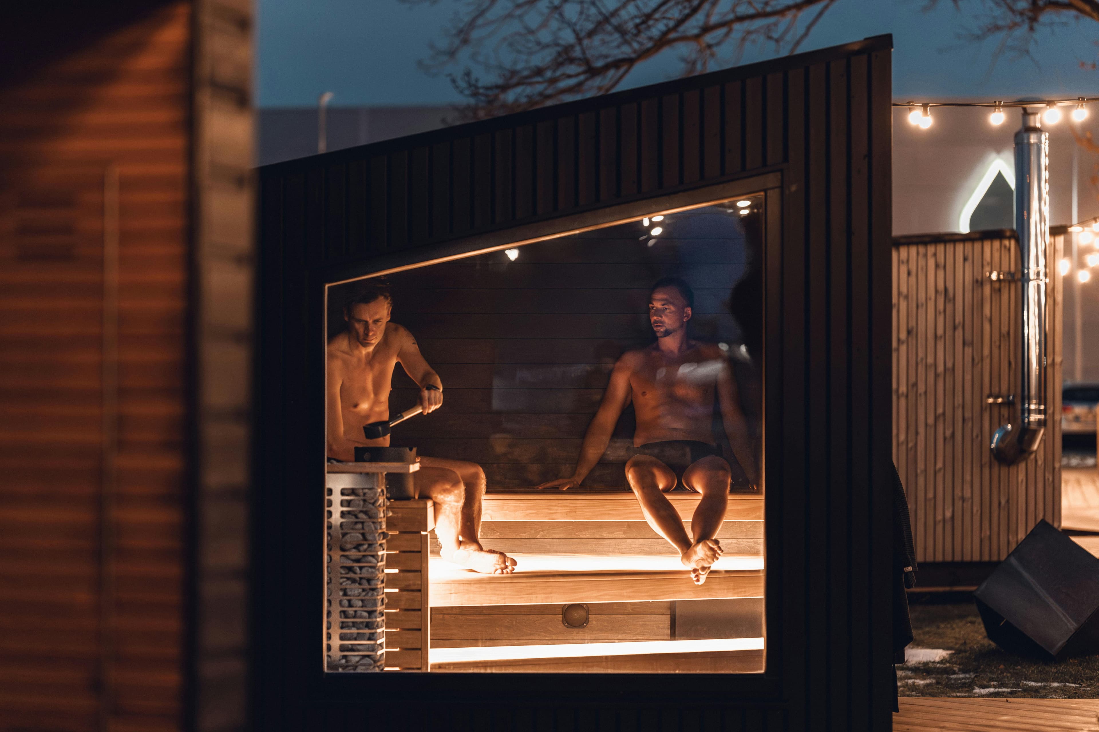 People in a wood-fired cabin sauna at night